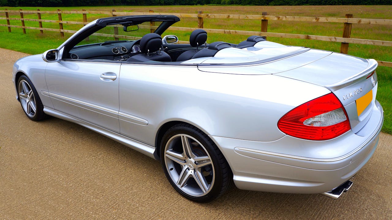Luxury silver convertible car parked on a countryside road, showcasing elegance and design.